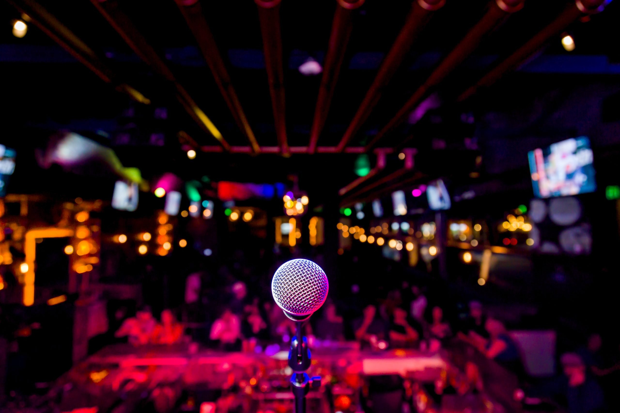 A microphone awaits its performer on a vibrant, colorfully lit stage, with an expectant audience in the background, all meticulously set up by a professional AV hire Preston.