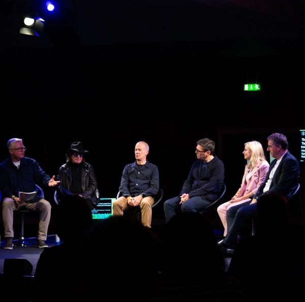 Panel discussion at an event with speakers engaged in conversation on stage, delving beyond the music.