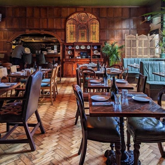An inviting and cozy vintage-style restaurant interior with rich wooden décor, stained glass windows, and state-of-the-art AV installation, ready to welcome diners.